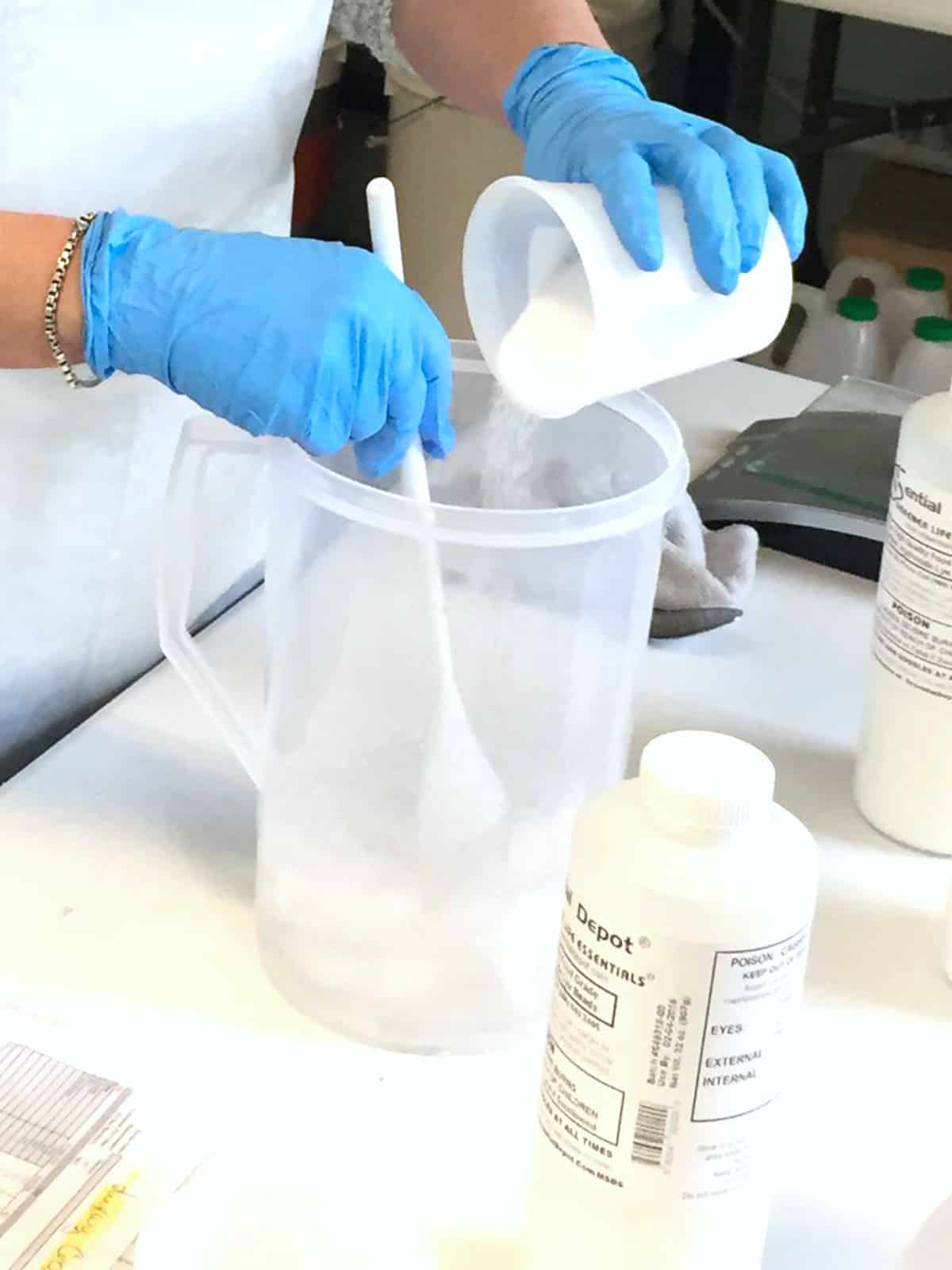 stirring measured sodium hydroxide into water for a lye solution.