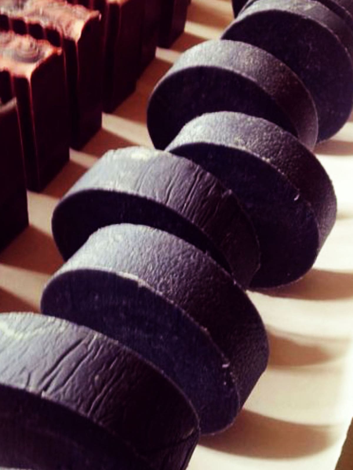 round Hockey puck charcoal soaps curing in a row.