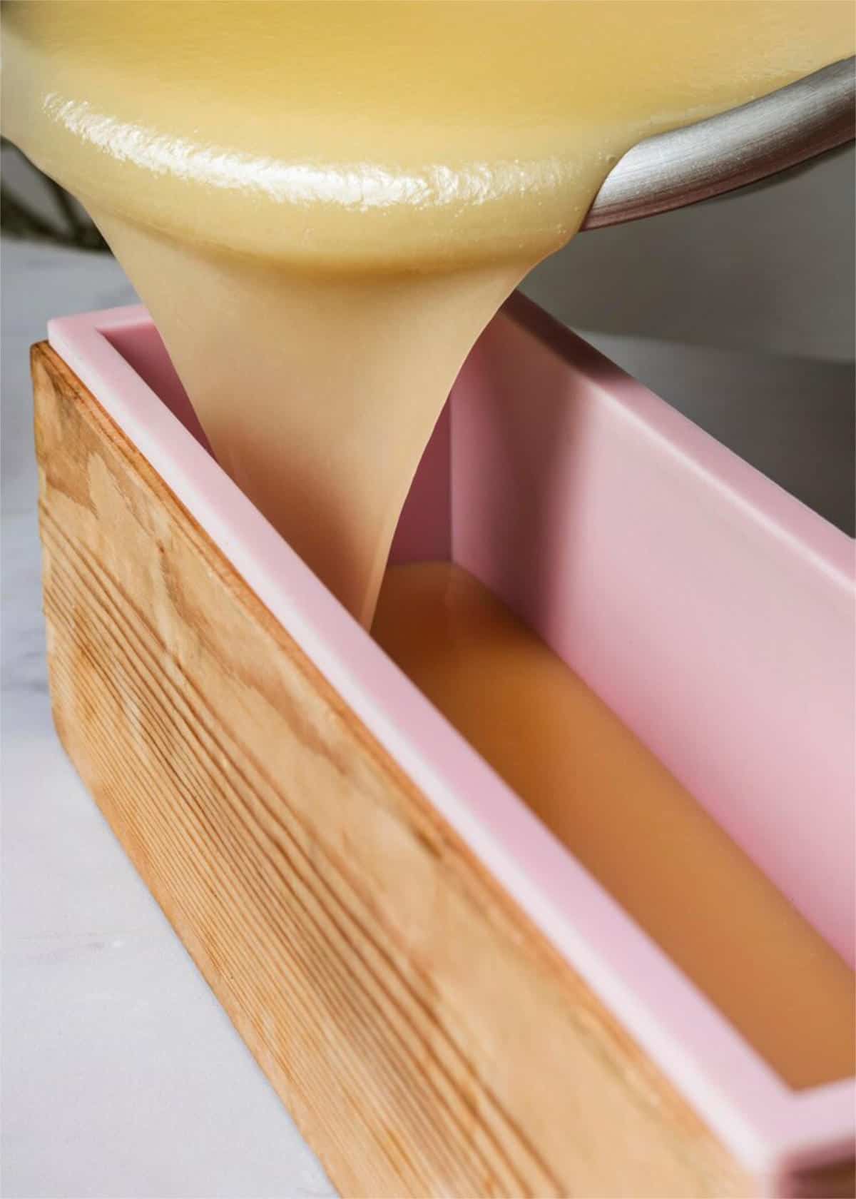 pouring yellow clay cold process soap into a log mold.